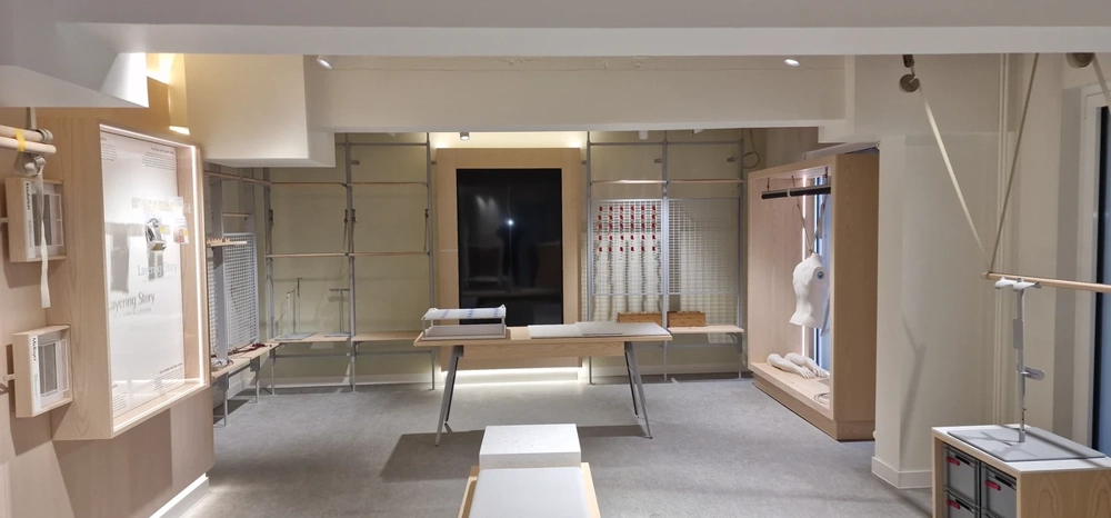 Ausgebaute Messewand mit Tisch, Kleiderpuppe und Regalsystemen – Beispiel für individuellen Messestandbau