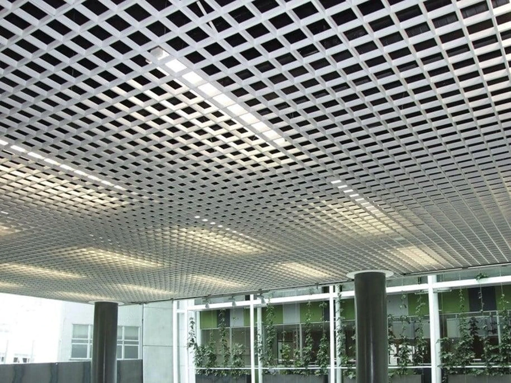 Weiße Rasterdecke aus quadratischen Gittern mit integrierten Deckenleuchten und Säulen im modernen Innenraum