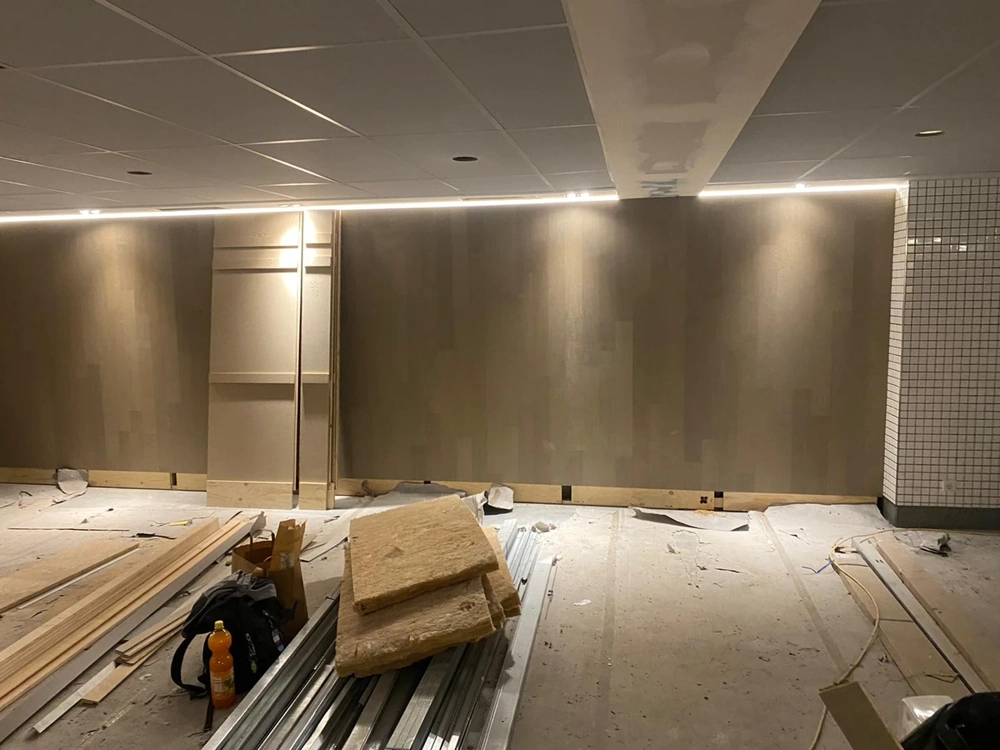 Installation einer abgehängten Decke mit sichtbaren Metallprofilen und Dämmplatten im Rohbau