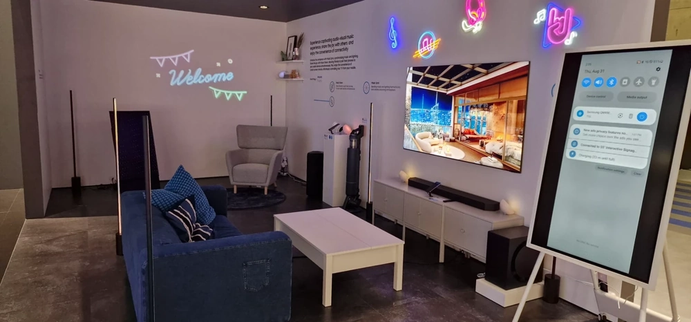 Messestand mit modernem Sofa, bequemem Sessel, Kaffeetisch, Wanddisplay und digitaler Stele