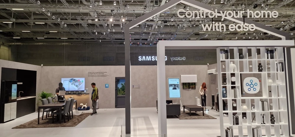Offener Messestandbau mit Lounge-Bereich, Trennwänden, digitalen Displays und Möbelelementen