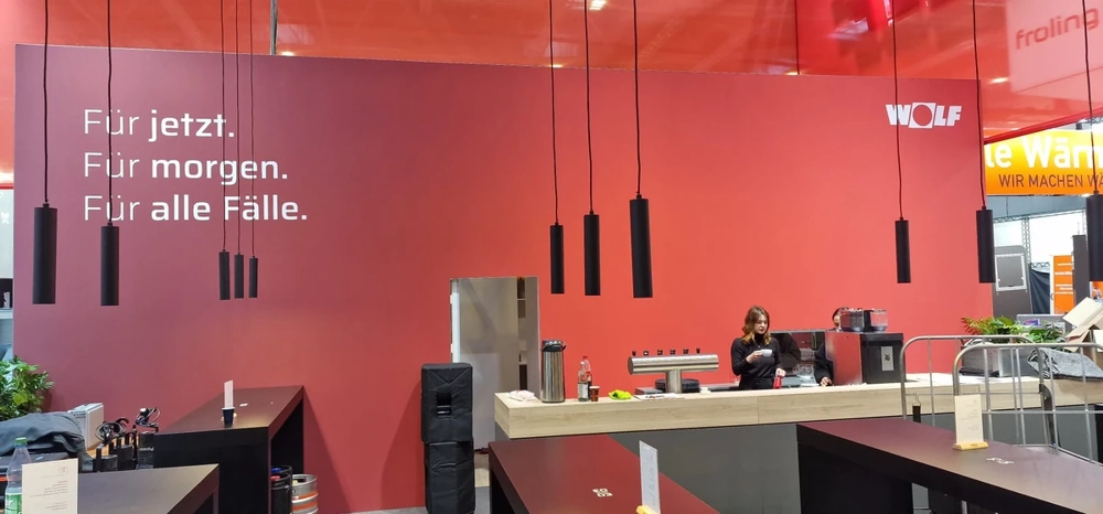 Messestand mit roter Rückwand, Bartheke und schwarzen Hängeleuchten