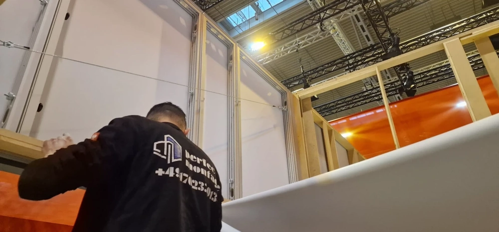 Handwerker installiert weiße Wandplatte in Metallrahmen bei Montage von wandsystemen