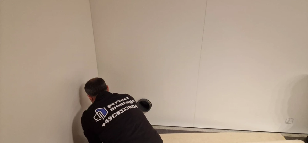 Montage von wandsystemen: Mitarbeiter installiert weiße Standwand in Raumecke