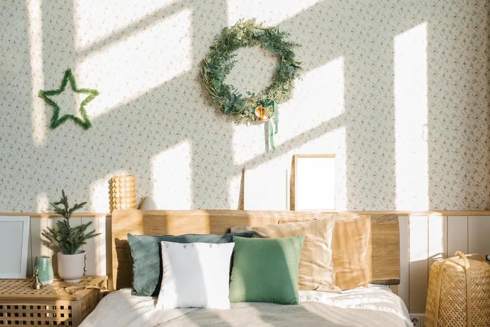 Sonniges Schlafzimmer mit Holzkopfteil, grün-weißen Kissen und Wandkranz