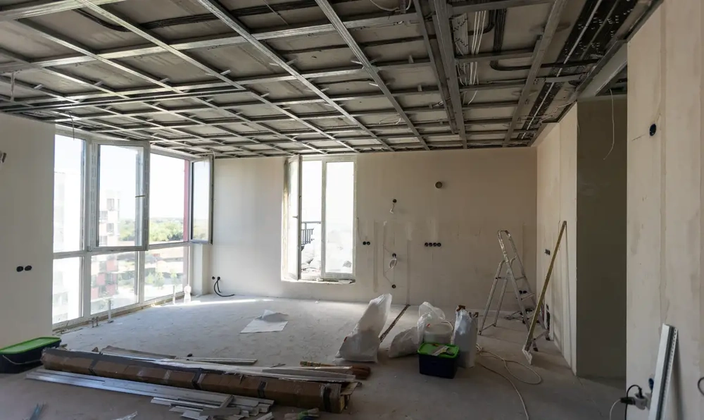 Innenraum im Rohbau mit montierter Metallunterkonstruktion für Rasterdecke, Kabeln und Baustellenmaterial